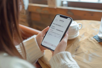 スマホでメール画面を確認している女性のイメージ写真
