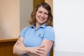 Dr. med. Sarah Kretschmann, an der Wand lehnend mit verschränkten Armen