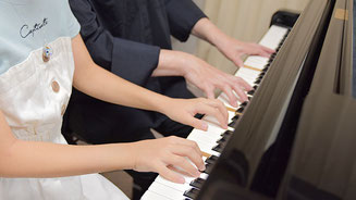 ピアノ講師と子供の生徒が連弾で演奏