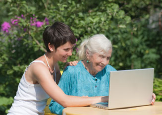 Alltagshilfe. Eine Seniorin und eine junge Frau gemeinsam am Computer.