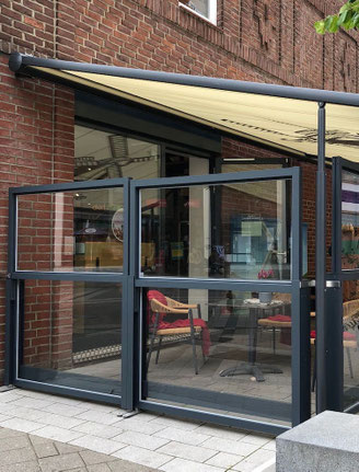 Terrasse mit in der Höhe verstellbarem Windschutz und einer passenden Markise