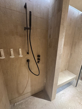 Douche réalisée en plaquettes de pierres naturelles françaises, avec banc et sol