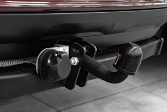 alt="Anhängerkupplung am Heck eines roten Autos montiert."