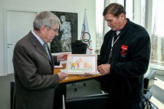 IOC-Präsident Dr. Thomas Bach erhält ein farbenfrohes Bild mit einem Elefanten und einem Löwen, die Volleyball spielen.