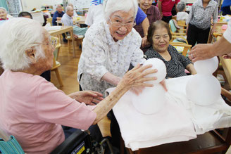普段見ない雪だるまを触り笑顔になる利用者=23日、デイサービスまなぶくん