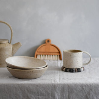 A table with handmade ceramic mug, bowls, and a table brush, inspired by slow living