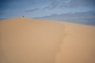 Ein Mann spaziert im weißen T-Shirt über die Sanddünen von Mui Ne.