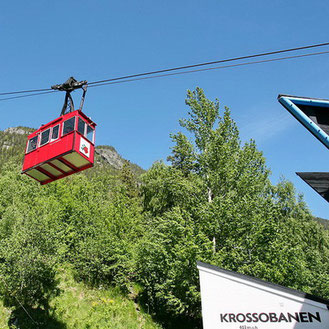 The red cabin of aerial tramway "Krossobanen" at Rjukan in front of a blue sky and green hills (photographer: Trond Strandsberg)