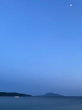 Besondere Abendstimmung am Meer mit Mond, Hügeln und Boot