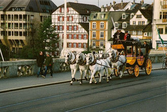 Postkutsche gezogen von 5 Schimmeln auf der mittleren Brücke in Basel