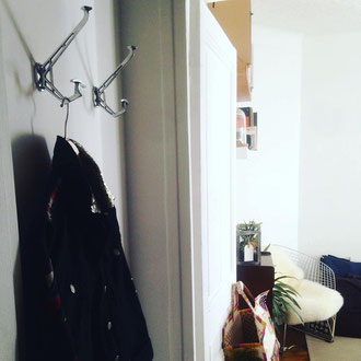 deux patères modèle Eiffel présentées dans une entrée d'appartement parisien contemporain aux murs blancs et mobilier design et vintage