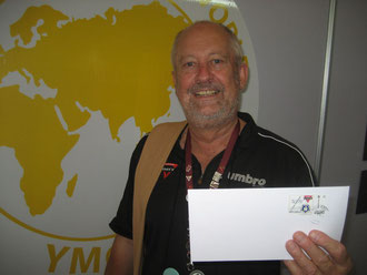 Eckard M.Geisler mit der CVJM-Briefmarke vor der Weltkarte. Der CVJM-Pensionär sammelt leidenschaftlich YMCA-Briefmarken