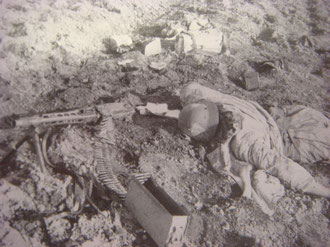 A dead German Grenadier lies behind his MG42