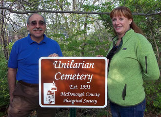 Heather McIlaine-Newsad (right), president of the board of the Unitarian Universalist Fellowship of Macomb, and Russell Hamm (left), treasurer, accepted the newest sign in the cemetery marking project sponsored by the McDonough County Historical Society.