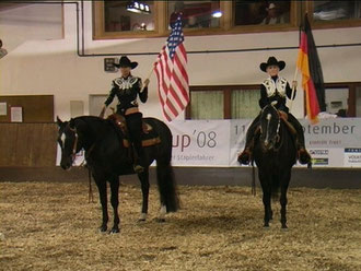 Den schwierigen Anfang unserer Show übernahmen Jasmin und Theresa, die in tollen, glitzernden Western-Outfits und riesigen Fahnen auf ihren Pferden einritten. Schlagartig funkelte ein Blitzlicht-Gewitter durch die abgedunkelte Halle.