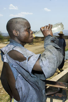 Saisonarbeiter aus Mosambik ernten Zuckerrohr unter Sklavenähnlichen Bedingungen im Süden Malawis. Sie nutzen das Wasser aus den Bewässerungsgräben als Trinkwasser, was zu Infektionen und Durchfällen führt. / Zucker - Malawi