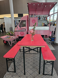 Pinke mobile Secco Ape mit Sitzgelegenheit auf einem Kongress im Innenbereich – strategisches Standkonzept, um den Messestand zum Place to be zu machen und Verweildauer zu erhöhen