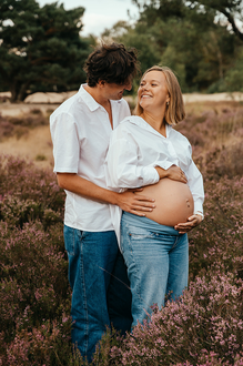 portret van zwanger koppel in de paarse heide waarbij ze verliefd naar elkaar kijken-zwangerschapsfotografie-©Fotografils-byIlseWagemakers-fotograaf-based in Essen, België