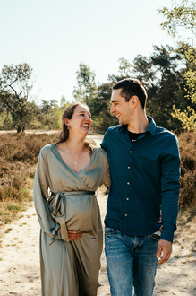 zwanger koppel lacht naar elkaar terwijl ze samen wandelen-zwangerschapsfotografie-©Fotografils-byIlseWagemakers-fotograaf-basedinEssen