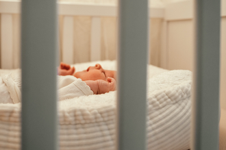detailfoto van handje baby, doorheen de spijlen van het babybedje gefotografeerd-babyreportage-newbornfotograaf-Fotografils-by Ilse Wagemakers-fotograaf Essen