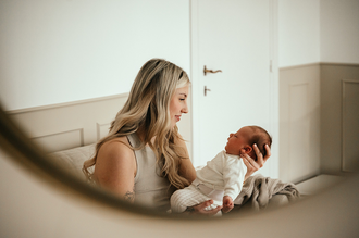mama houdt baby voor zich en bekijkt deze verliefd, gefotografeerd in een spiegel-babyreportage-newbornfotograaf-Fotografils-by Ilse Wagemakers-fotograaf Essen