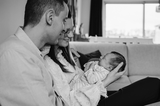 mama houdt baby voor zich uit en kijkt er samen met papa verliefd naar, de baby glimlacht-babyreportage-newbornfotografie-Fotografils-by Ilse Wagemakers-fotograaf Essen