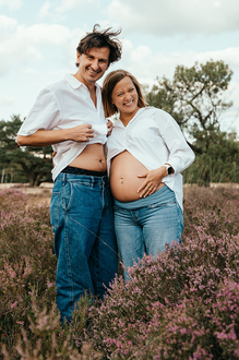 grappig portret van zwanger koppel in de paarse heide waarbij de man ook zijn ontblote buik toont-zwangerschapsfotografie-©Fotografils-byIlseWagemakers-fotograaf-based in Essen, België