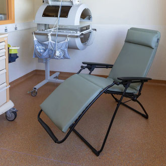 Fauteuil relax Lafuma vert sauge installé dans une chambre de néonatologie, à côté d'une couveuse pour nouveau-nés
