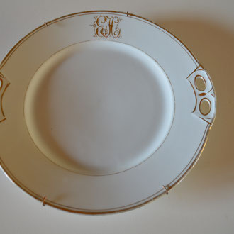 Kuchenplatte, die mittels dazugehöriger Halterung auch als Wandteller genutzt werden kann. Um 1910. Mit Monogram EH. Preis: VB 8,00 €