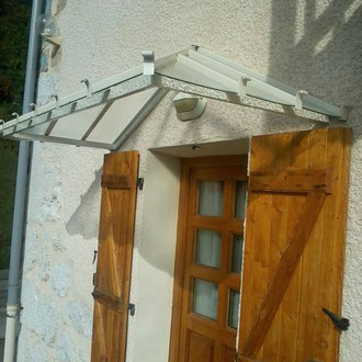 Structure vitrée soutenue par une marquise en aluminium, idéale pour une entrée de maison moderne.