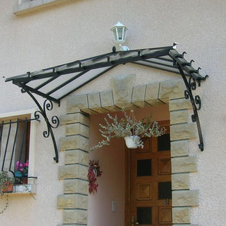 Marquise en aluminium moderne et légère, couvrant une porte d’entrée pour la protéger des intempéries