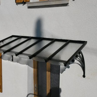 Marquise en fer forgé montée sur façade de maison, parfaite alliance entre esthétique et fonctionnalité.