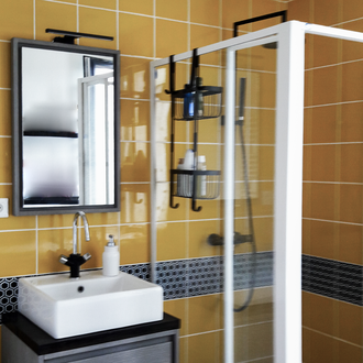 Salle de bain rénovée, dans une maison de pêcheur au Tréport, en Normandie, avec carrelage jaune, douche vitrée, vasque blanche et robinetterie noire – décoration et aménagement intérieur.