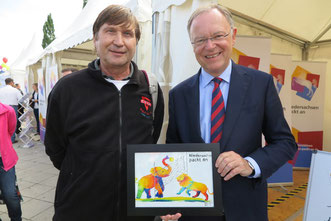 Ein Bild mit Symbolkraft mit friedlich Volleyball spielenden Elefanten und Löwen für Ministerpräsidenten Stephan Weil von Sozialvolleyballer Manfred Wille beim Tag der Niedersachsen  2017