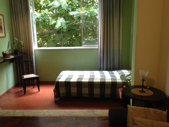cama de solteiro na varanda, com uma mesinha de cabeceira e abajur 