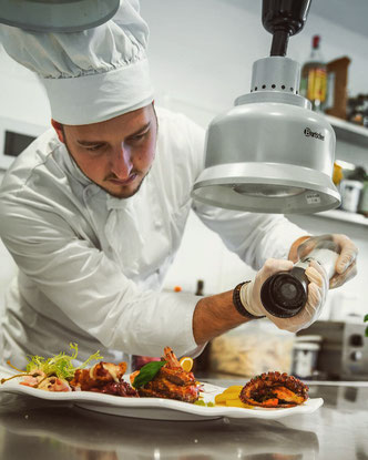 Der Koch des Ristorante La Volpe, Riccardo Piazzoli, richtet ein Gericht in der Küche an und würzt es. 