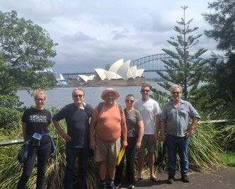 Tour group and guide posing in Sydney Botanical Gardens with Opera House and Harbour Bridge in background