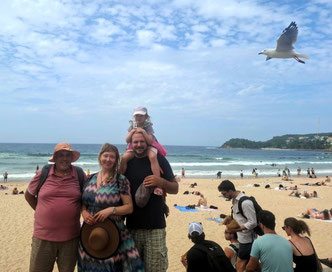 Four beachgoers with seagull in background at Manly Beach, Sydney