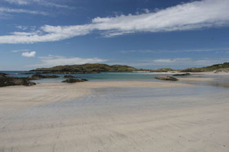 Breiter weißer Sandstrand, Derrynane Beach am Ring of Kerry in Irland mit ein paar flachen, vom Meer umspülten Felsen im Hintergrund und blauem Himmel mit weißen Wolken ©My own Travel