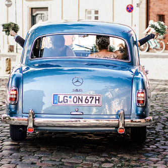 glückliches Paar im Oldtimer Hochzeitsauto nach der Trauung im Wasserturm Lüneburg