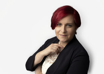 Professional business portrait of a red-haired woman on a seamless white background. A modern, minimalist corporate headshot ideal for company websites and team directories.