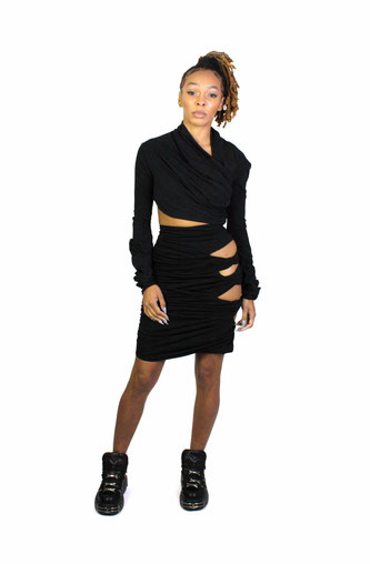 model wears a twisted crop top and cut out skirt in black