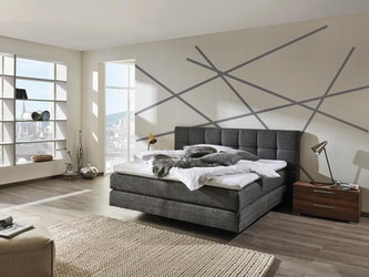 Dicke Polsterungen lassen das Rückenteil des Bettes der Kollektion mySUITEhome von Hülsta wie ein bequemes Sofa wirken. Foto: www.huelsta.de