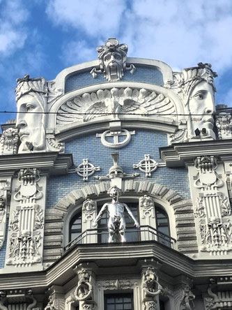 Detail of Art Nouveau building in Riga with sculptures of human heads and a peacock