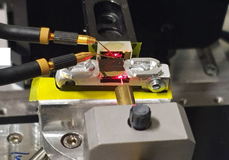 Ein roter Laser macht den Strahlengang von der Faser in den Lichtwellenleiter und die Reflexion an einem Goldspiegel sichtbar. Die zwei Mikrosonden kontaktieren den Fotoleiter, der eine Grösse im Subwellenlängenbereich aufweist. Bild: Empa 