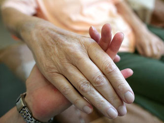 Die Hand einer alten Frau wird von einer Pflegerin gehalten. Foto: Jens Wolf/Archiv