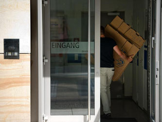 Ein Polizist trägt Kartons in das Gebäude des Dating-Portal Lovoo in Dresden. Foto: Arno Burgi