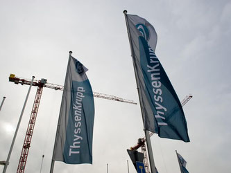 Fahnen mit dem ThyssenKrupp-Logo vor einer Produktionshalle des Konzerns. Foto: Inga Kjer
