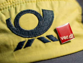 Ein Pin der Gewerkschaft Verdi an der Kappe einer Post-Mitarbeiterin. Foto: Christian Charisius