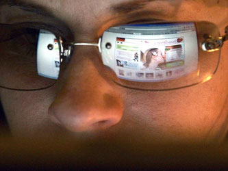 So flirtet man heute: In der Brille einer jungen Frau spiegelt sich die Seite einer Online-Singlebörse. Foto: Frank May/Archiv